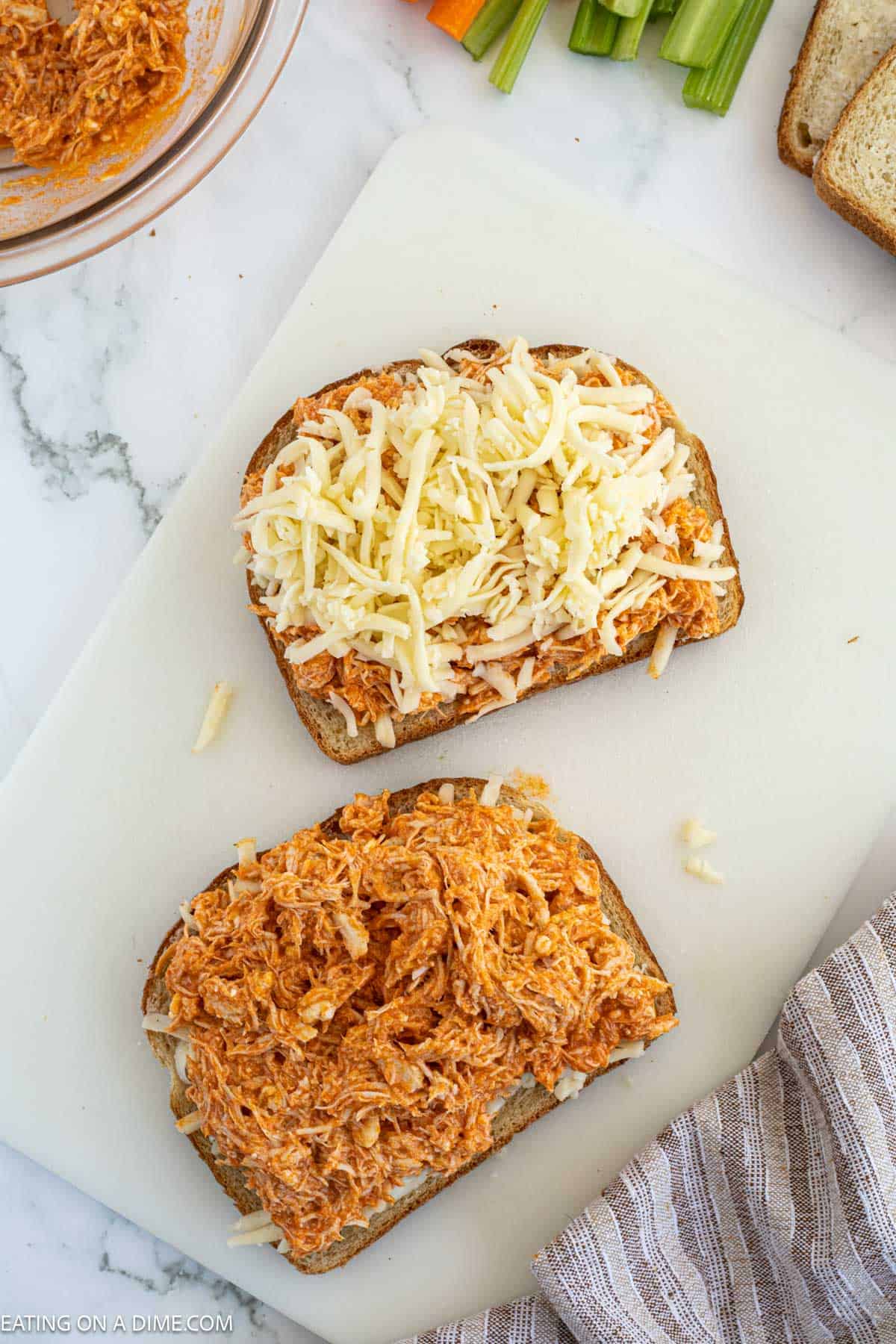 Topping bread with shredded buffalo chicken and shredded cheese
