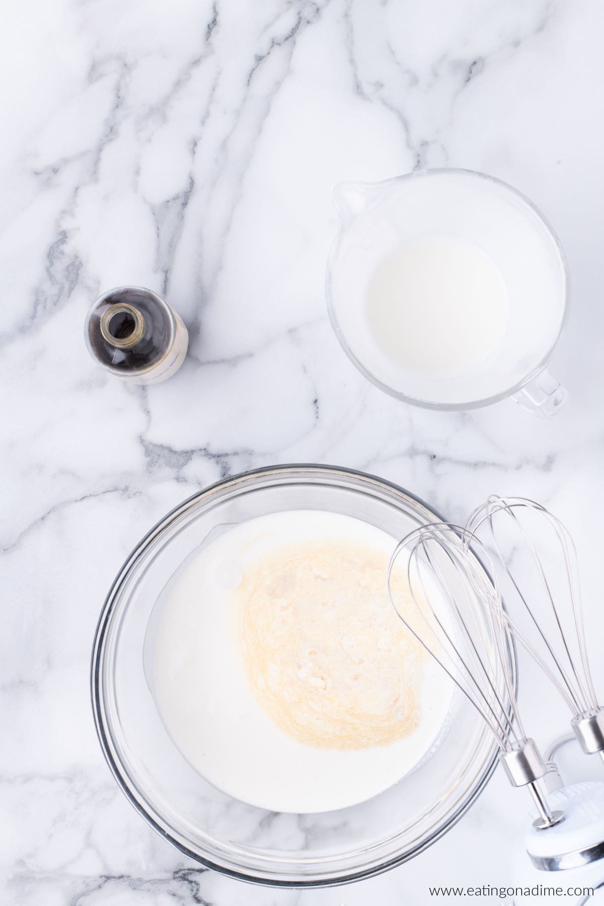 Heavy cream and vanilla extract added to a bowl.