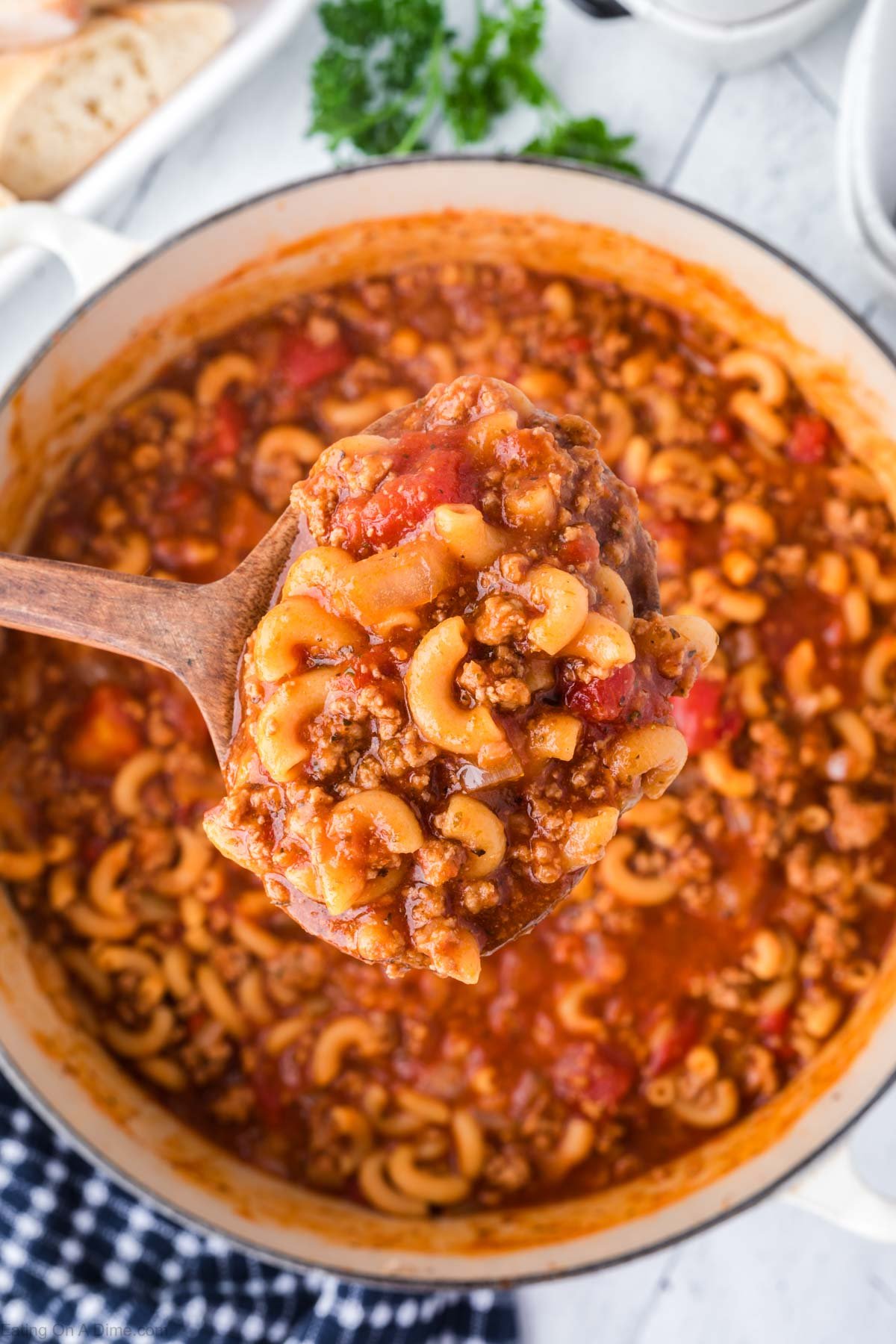 Goulash in a large pot with a serving in a wooden spoon