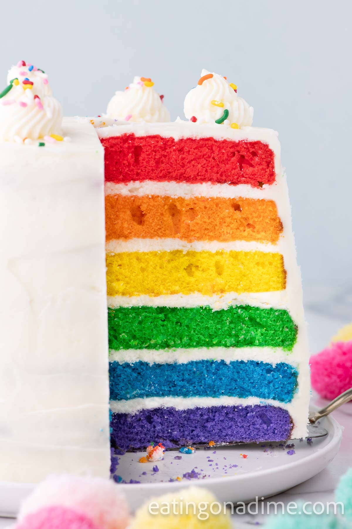 Close up image of frosted Rainbow Cake sliced to see all the layers