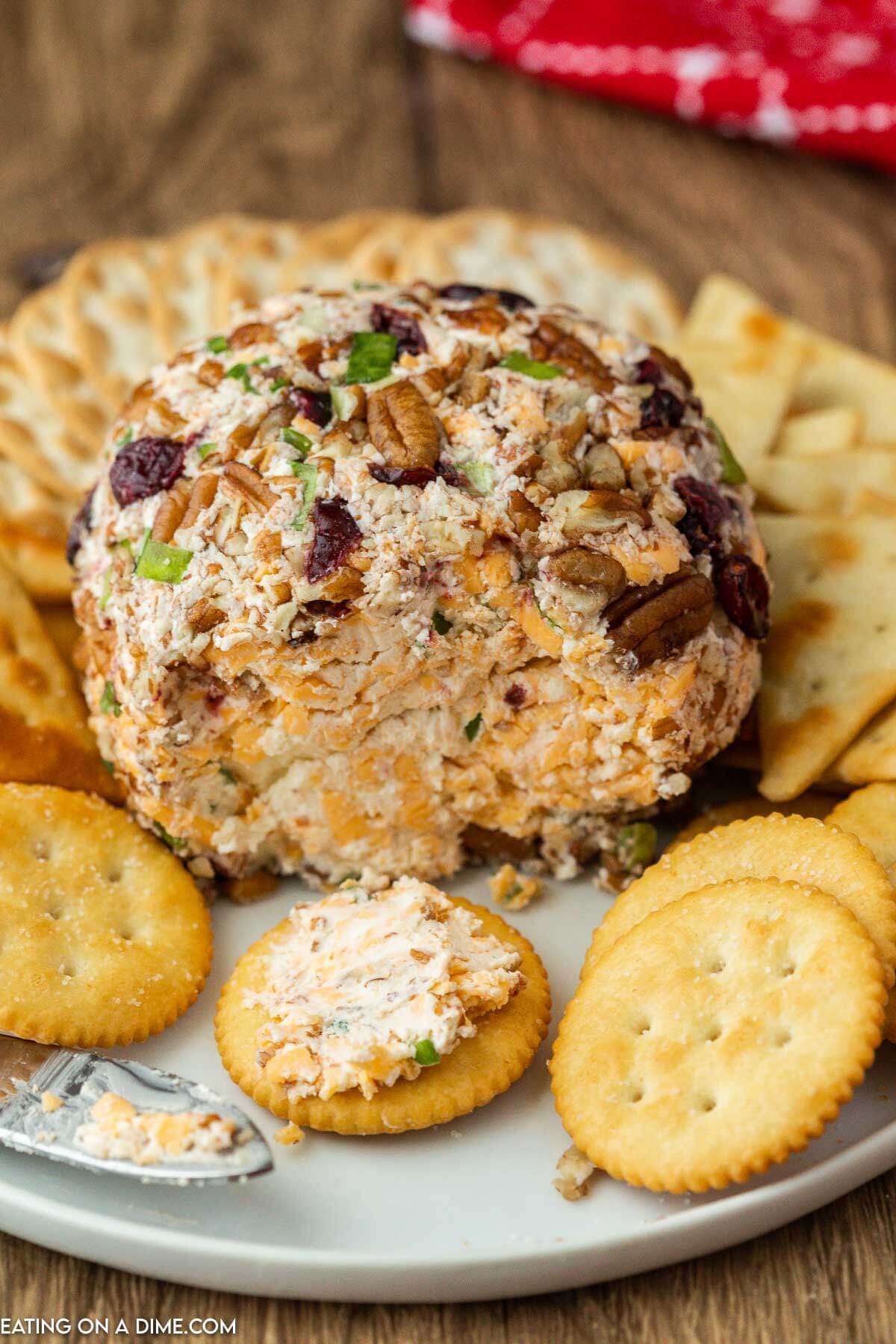 Christmas Cheese Ball on a platter with a side of crackers with a serving on a cracker
