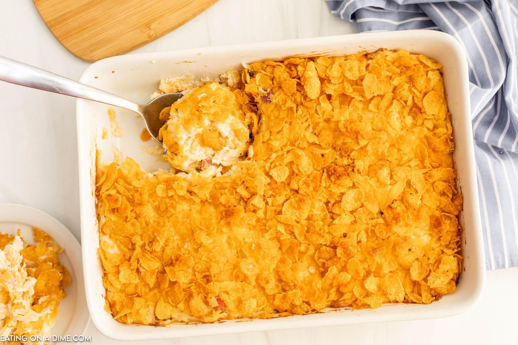 Funeral potatoes in a baking dish with a spoon