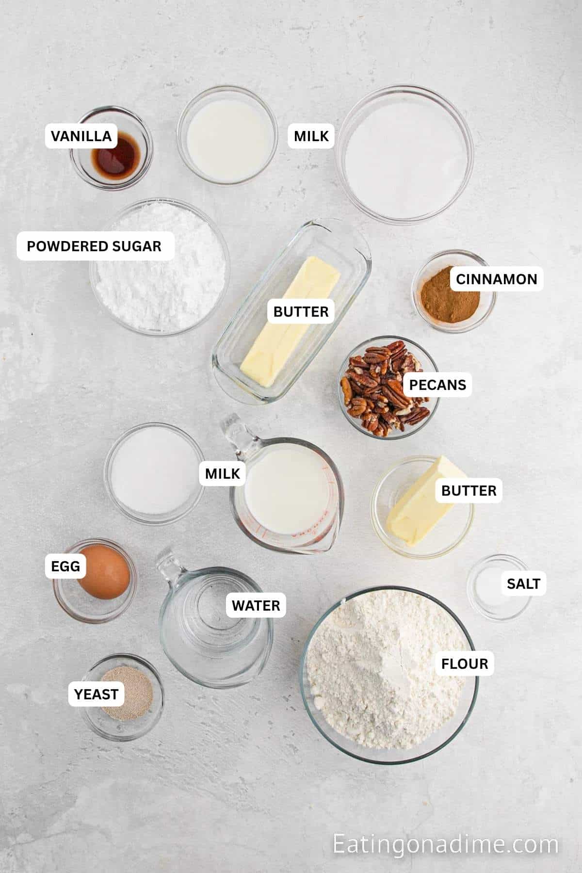 Ingredients for recipe: powdered sugar, vanilla, milk, butter, cinnamon, pecans, milk, egg, yeast, salt and flour.