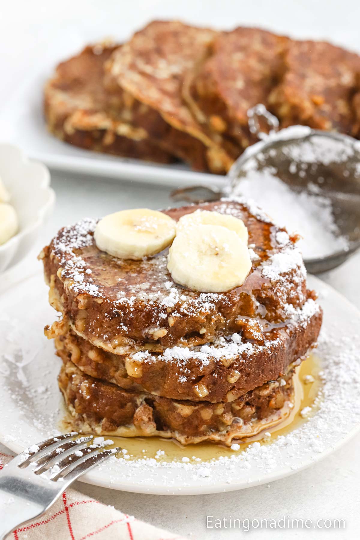 Banana Bread French Toast on a plate topped with slice bananas and syrup