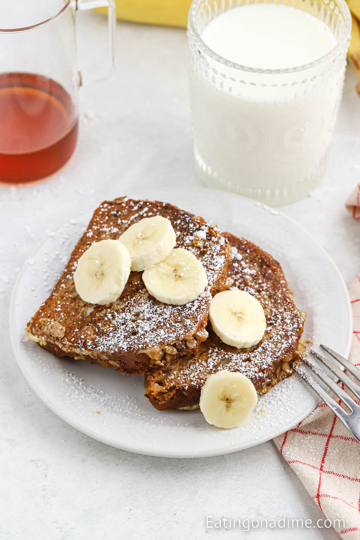 Banana Bread French Toast on a plate topped with slice bananas and powdered sugar