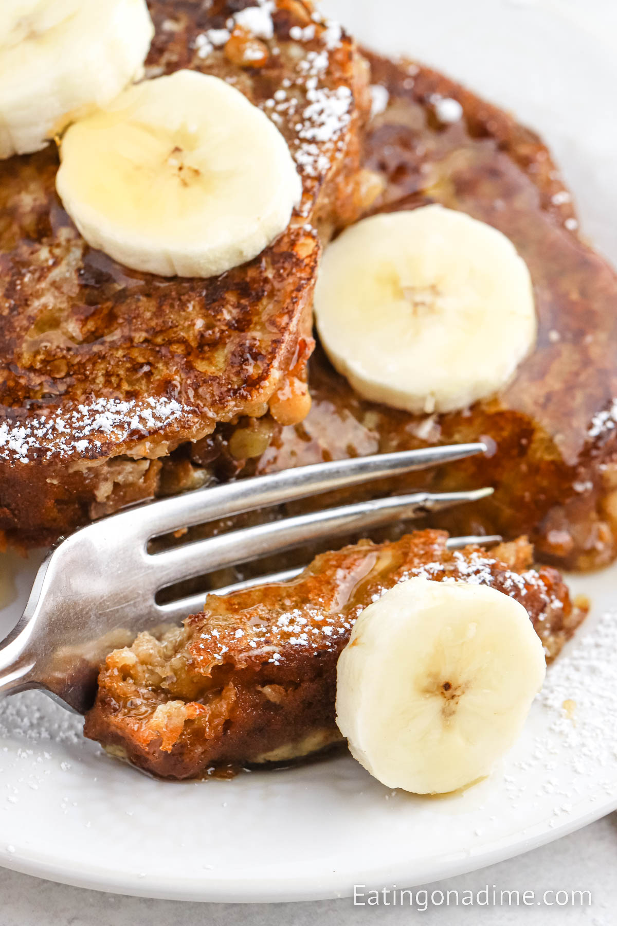 Banana Bread French Toast on a plate topped with slice bananas and syrup