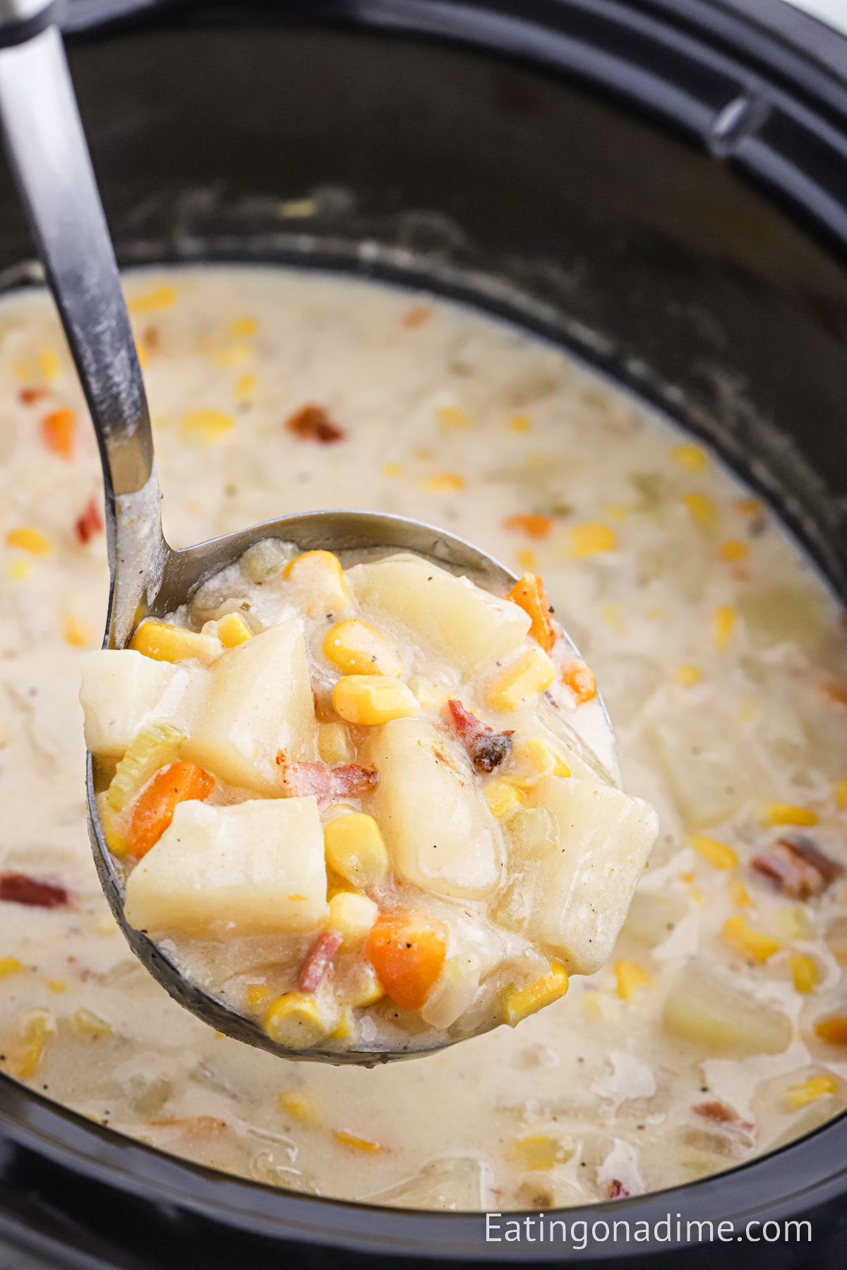 Potato and corn chowder in the crock pot with a serving on a ladle