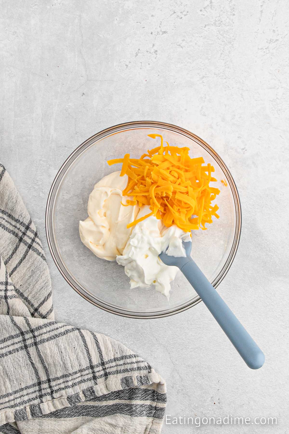 Combining the sour cream and mayo with the cheese in a bowl