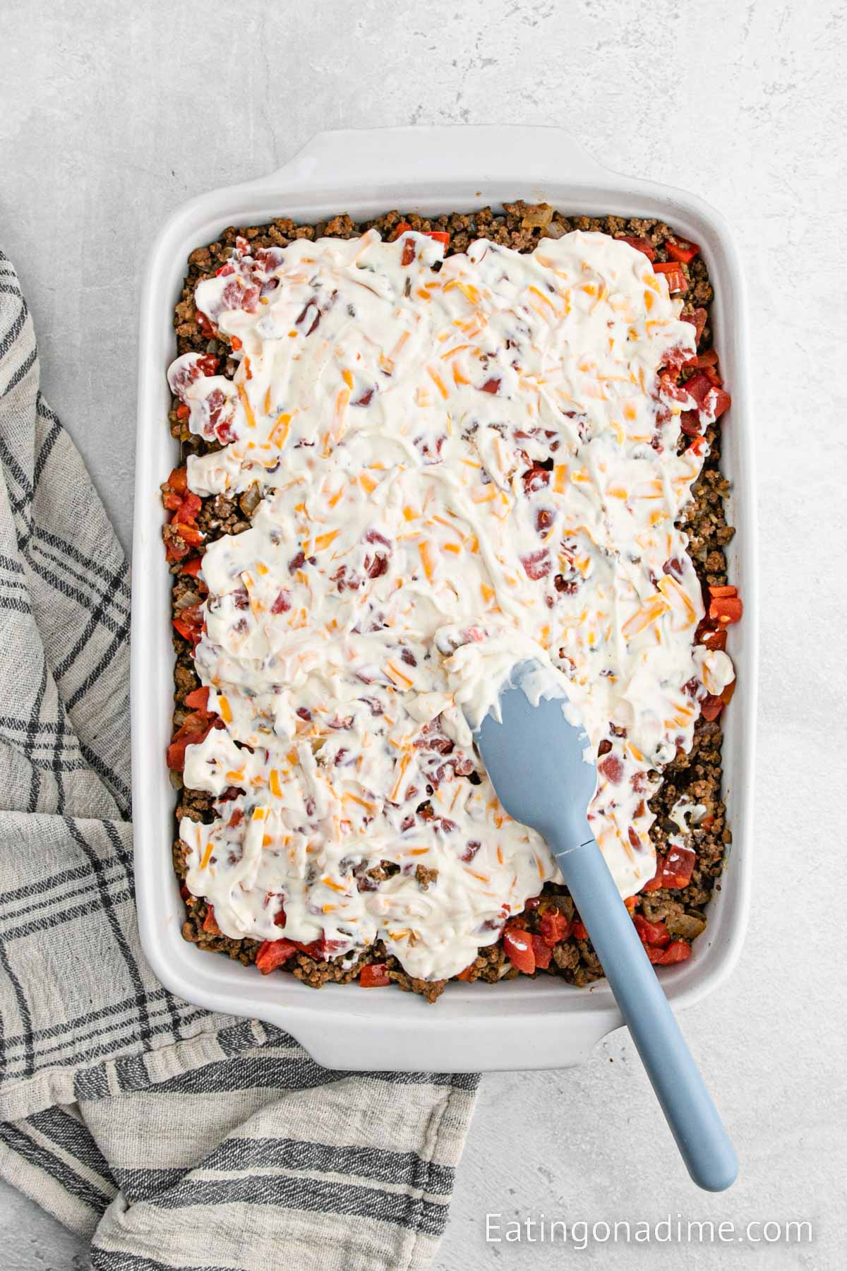 Spreading the sour cream mixture over the top of the beef layer