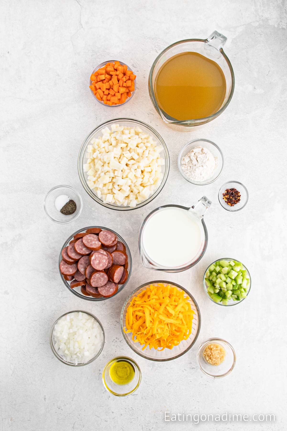 Ingredients needed to make potato and kielbasa soup - Olive oil, sausage, onion, carrots, celery, garlic, flour, chicken broth, hash browns red chili flakes, milk, salt, pepper, cheese