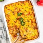 king ranch chicken casserole being scooped by a wooden spoon, cloth napkin next to the casserole.