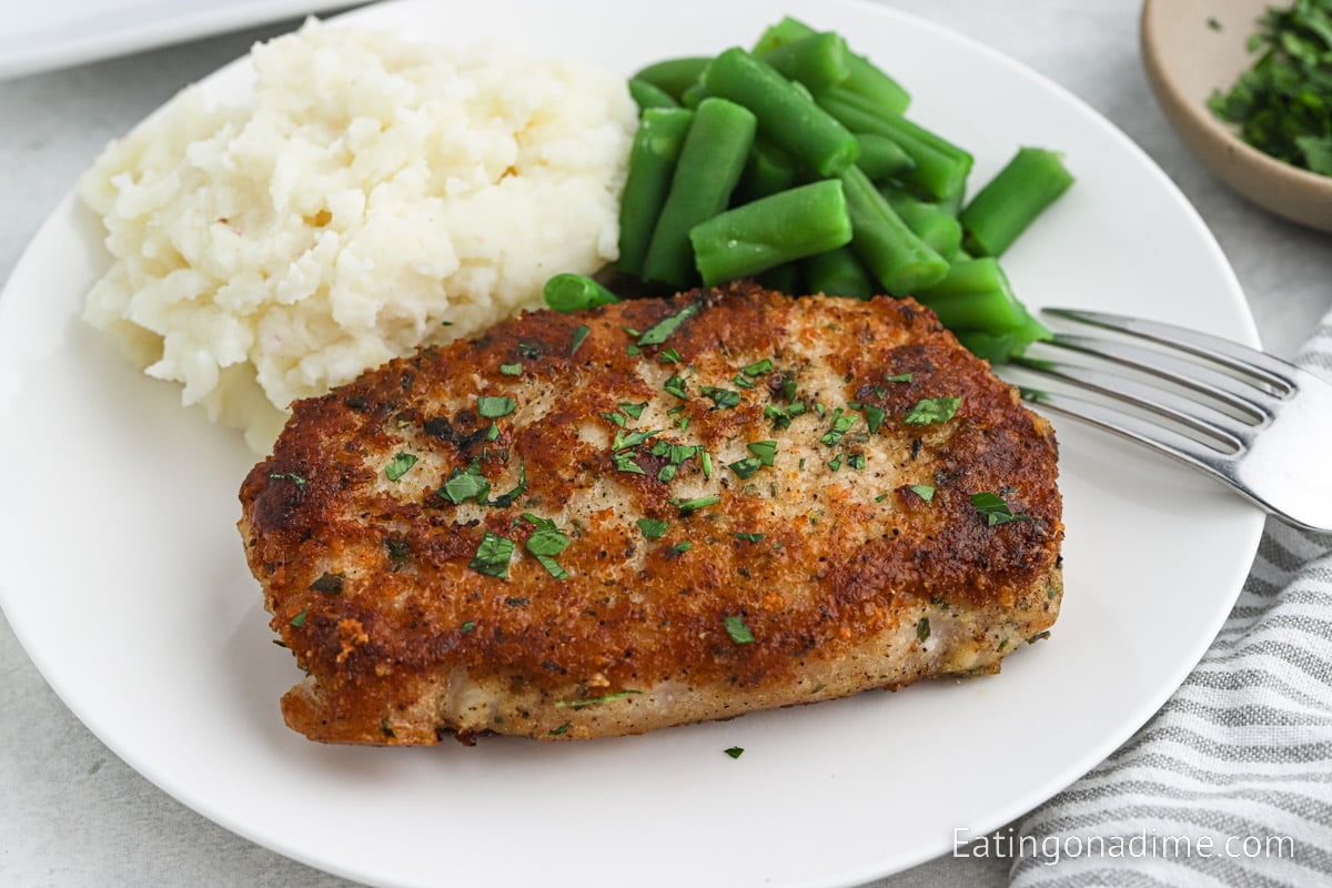 Parmesan Crusted Pork Chops on a plate with green beans and mashed potatoes