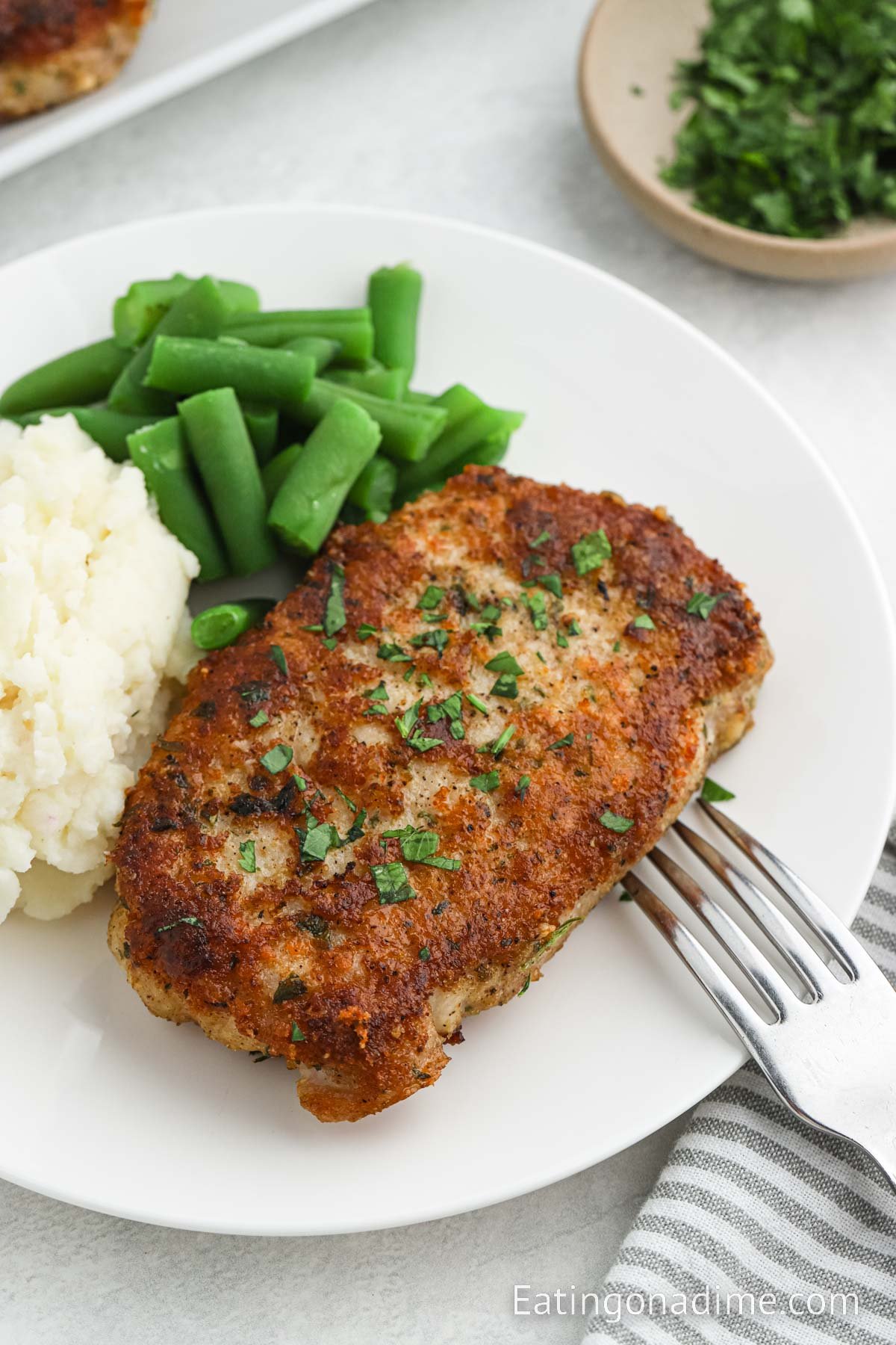 Parmesan Crusted Pork Chops on a plate with green beans and mashed potatoes