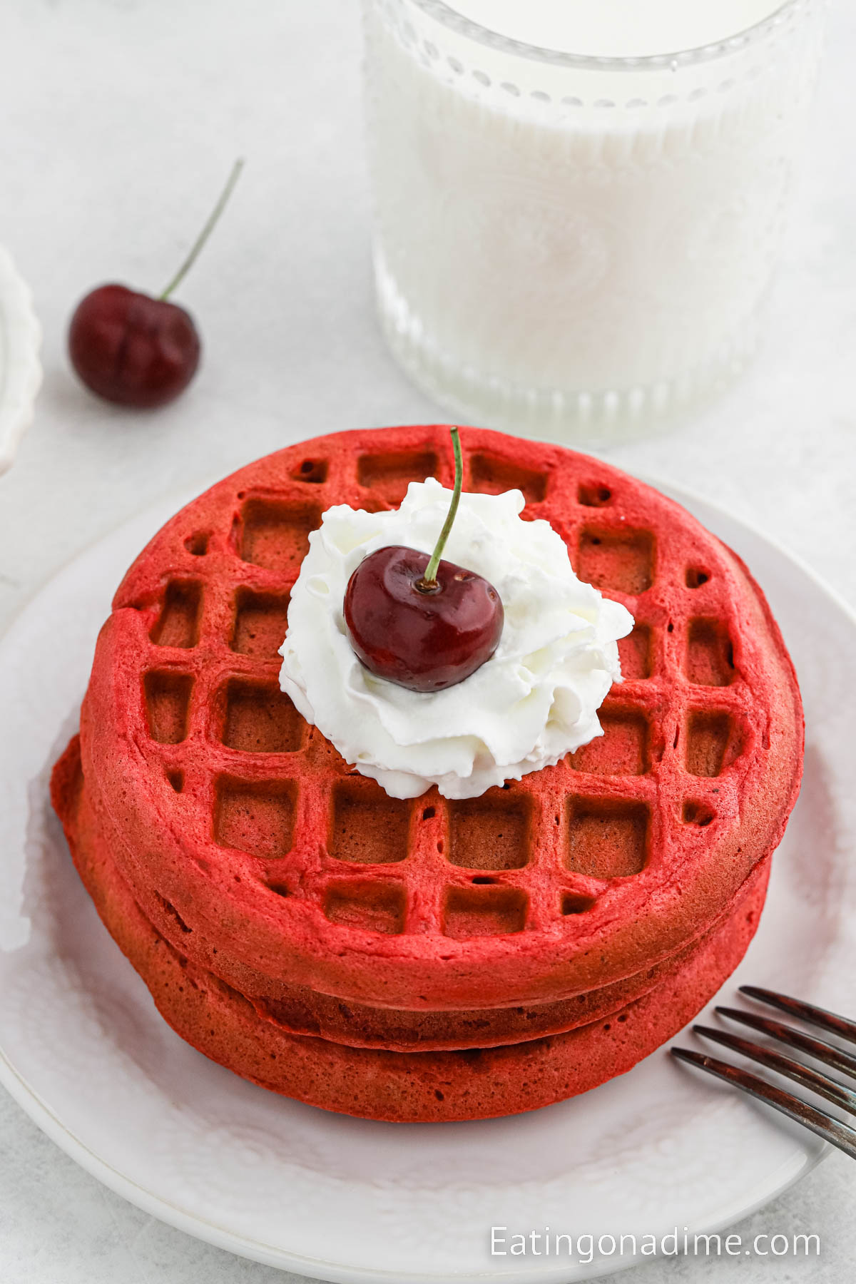 Red Velvet Waffles Stacked and topped with cream cheese glaze and a cherry
