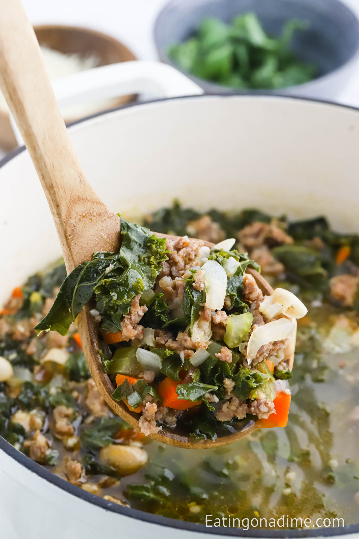 Sausage Kale White Bean Soup in a large pot with a wooden spoon