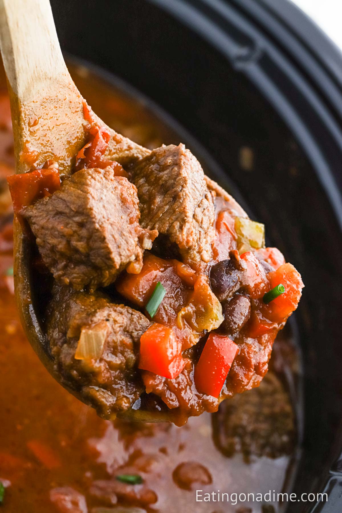Brisket Chili in the slow cooker with a serving on a ladle.
