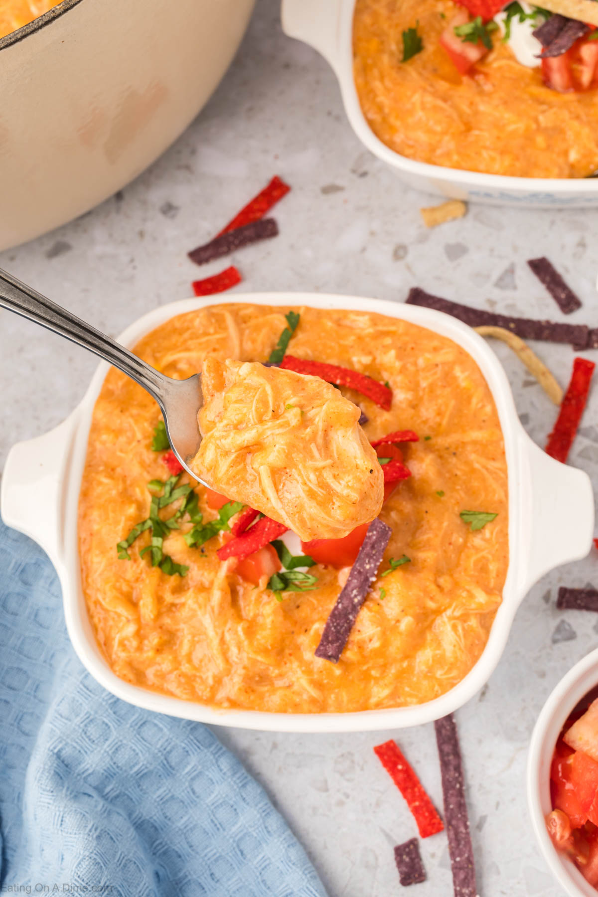 Chicken Enchilada Soup in a bowl topped with tortilla strips, cilantro and serving on a spoon