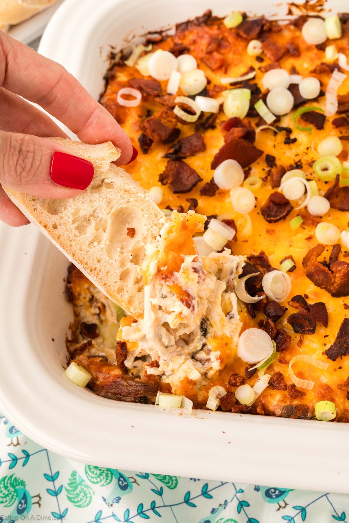 Crack Chicken Dip in a baking dish with french bread being dipped into it