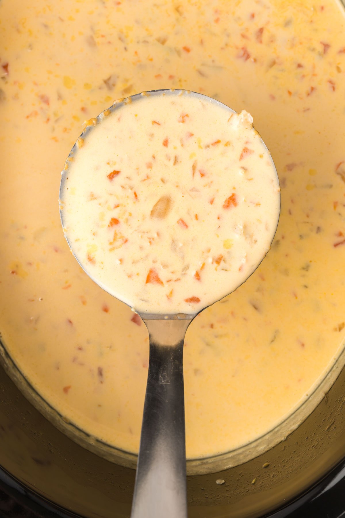 Close up image of beer cheese soup in the slow cooker with a serving on a ladle