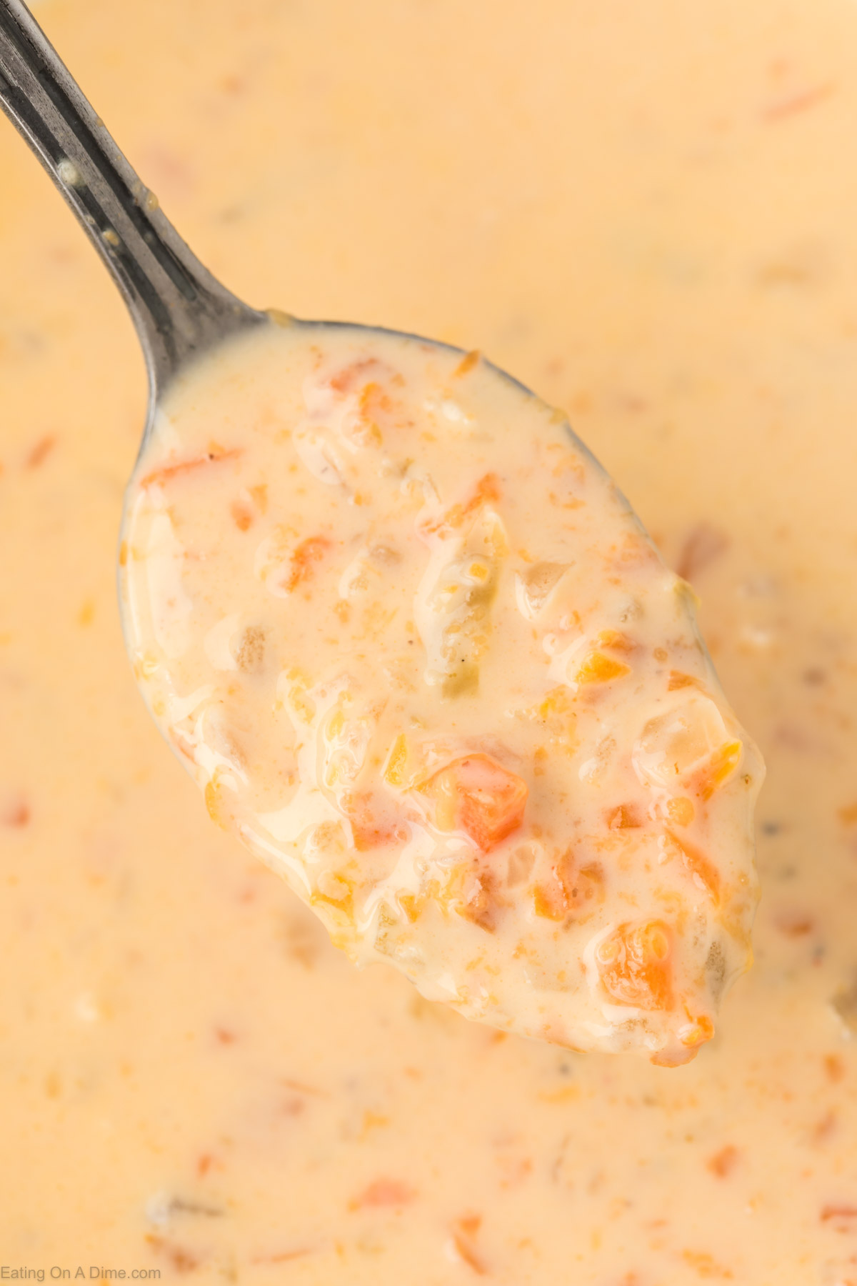 Close up image of a serving of beer cheese soup on a large spoon