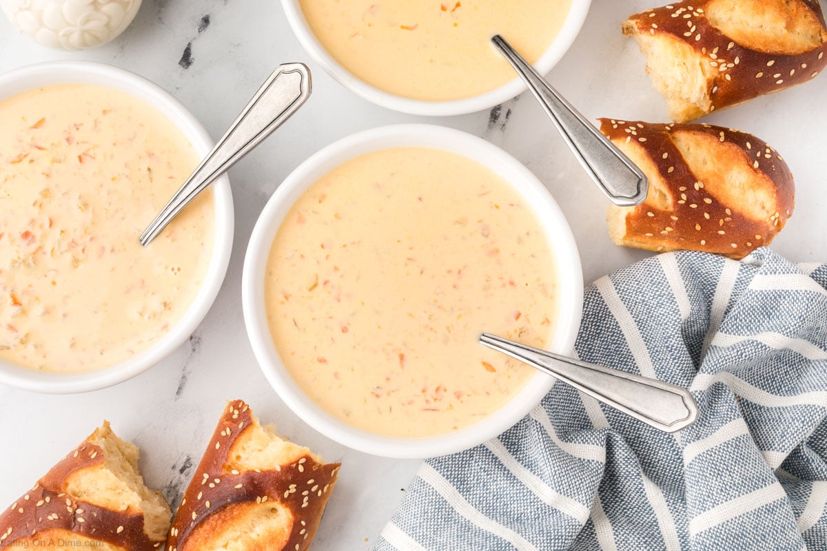 Bowls of Beer Cheese Soup with sides of pretzel rolls