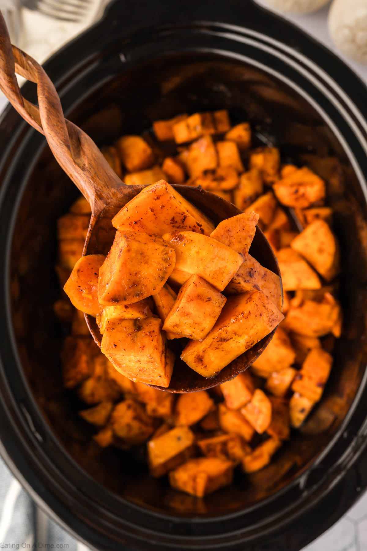 Candied Yams in a slow cooker with a wooden spoon