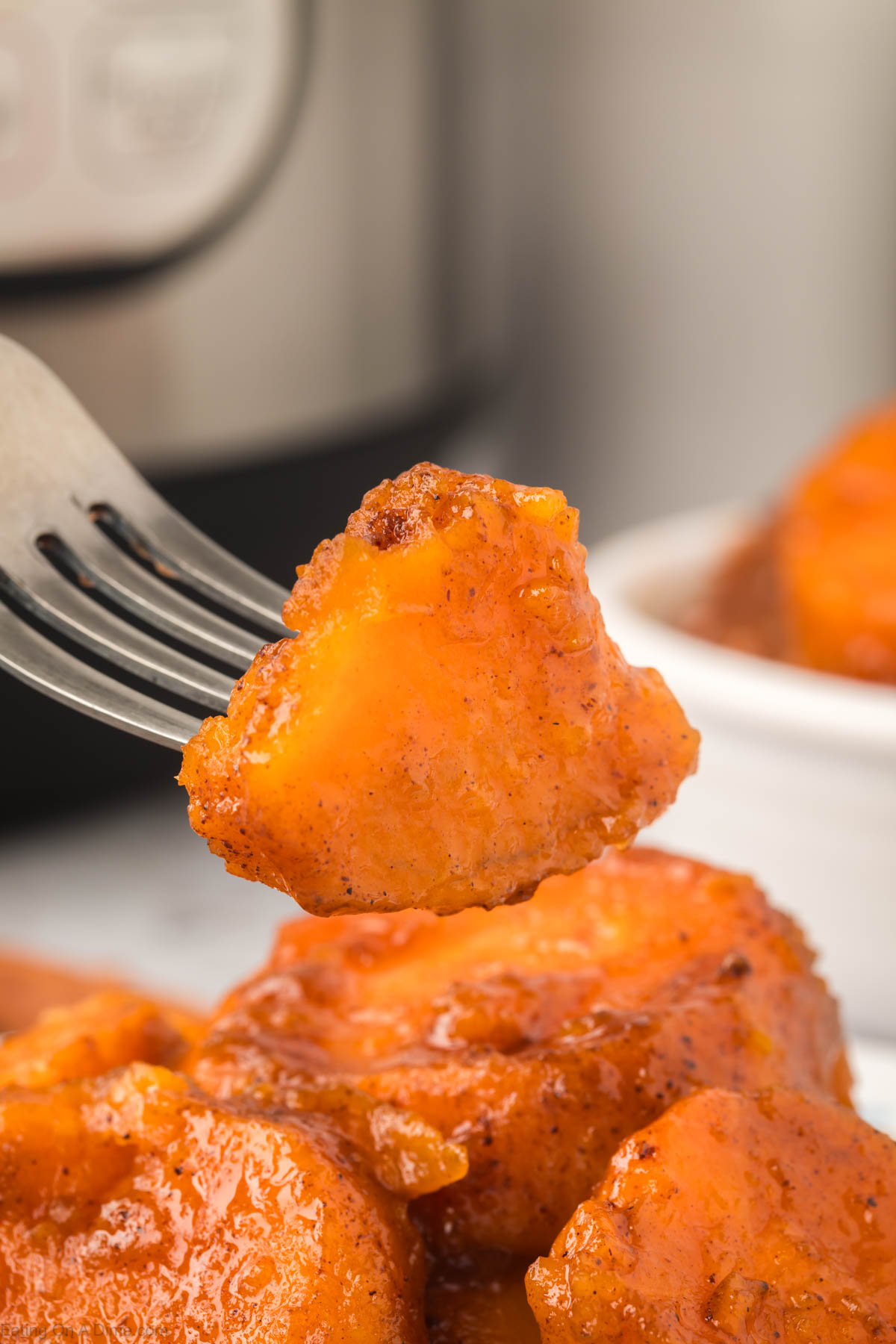Close up image of candied yams with a bite on a fork