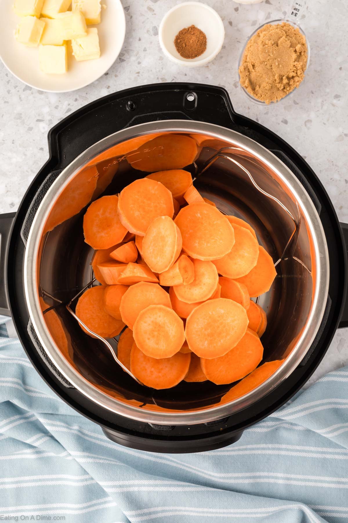Slice yams placed in the instant pot with a plate of butter and a bowl of cinnamon and brown sugar