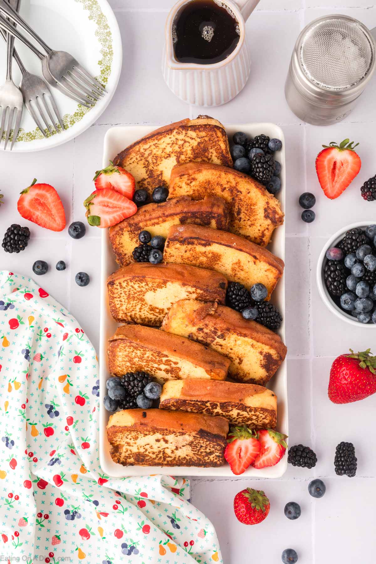 Pound Cake French Toast Slices on a platter with fresh blueberries, blackberries, and strawberries on the side