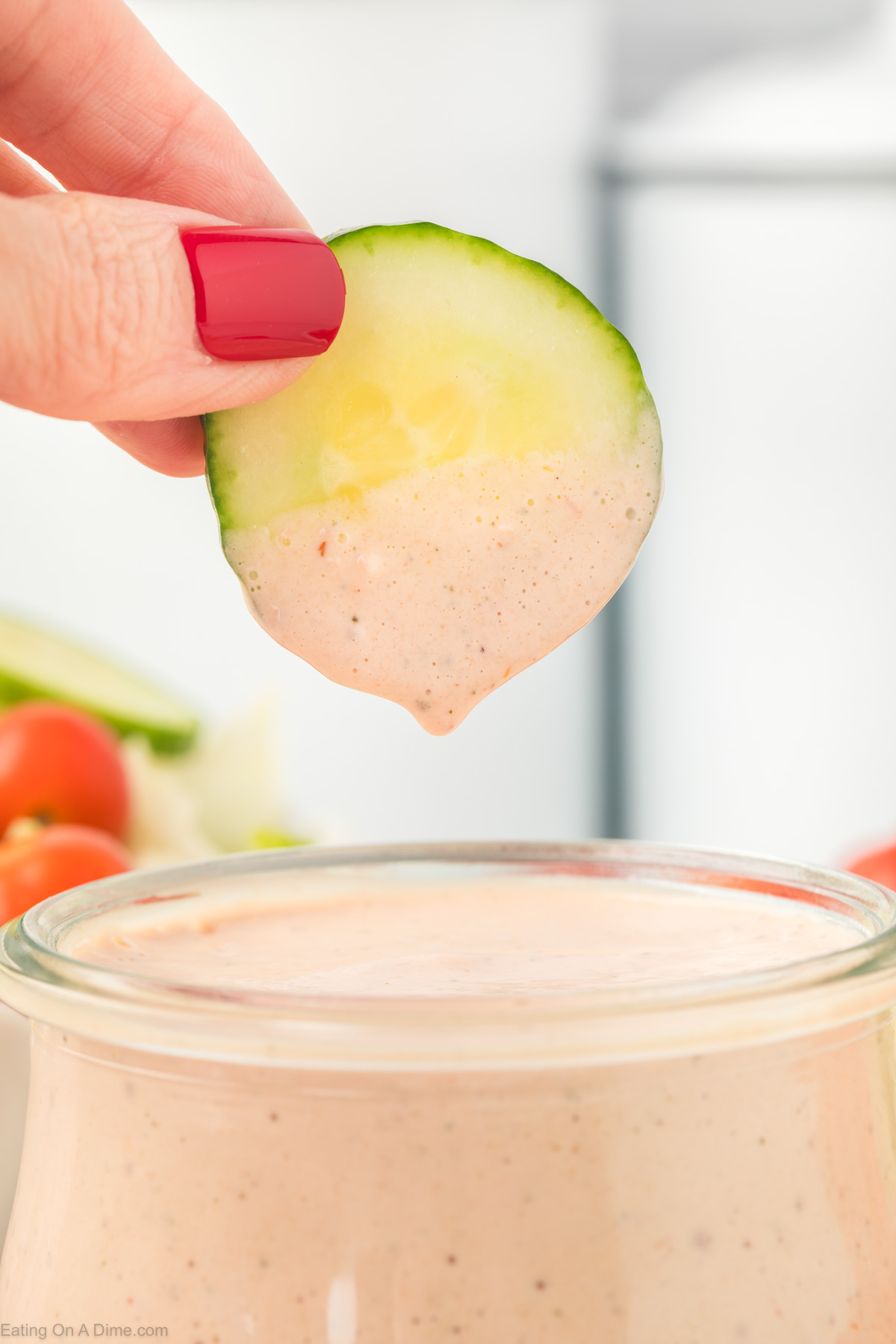 Dipping slice cucumber in a jar of salsa ranch dressing