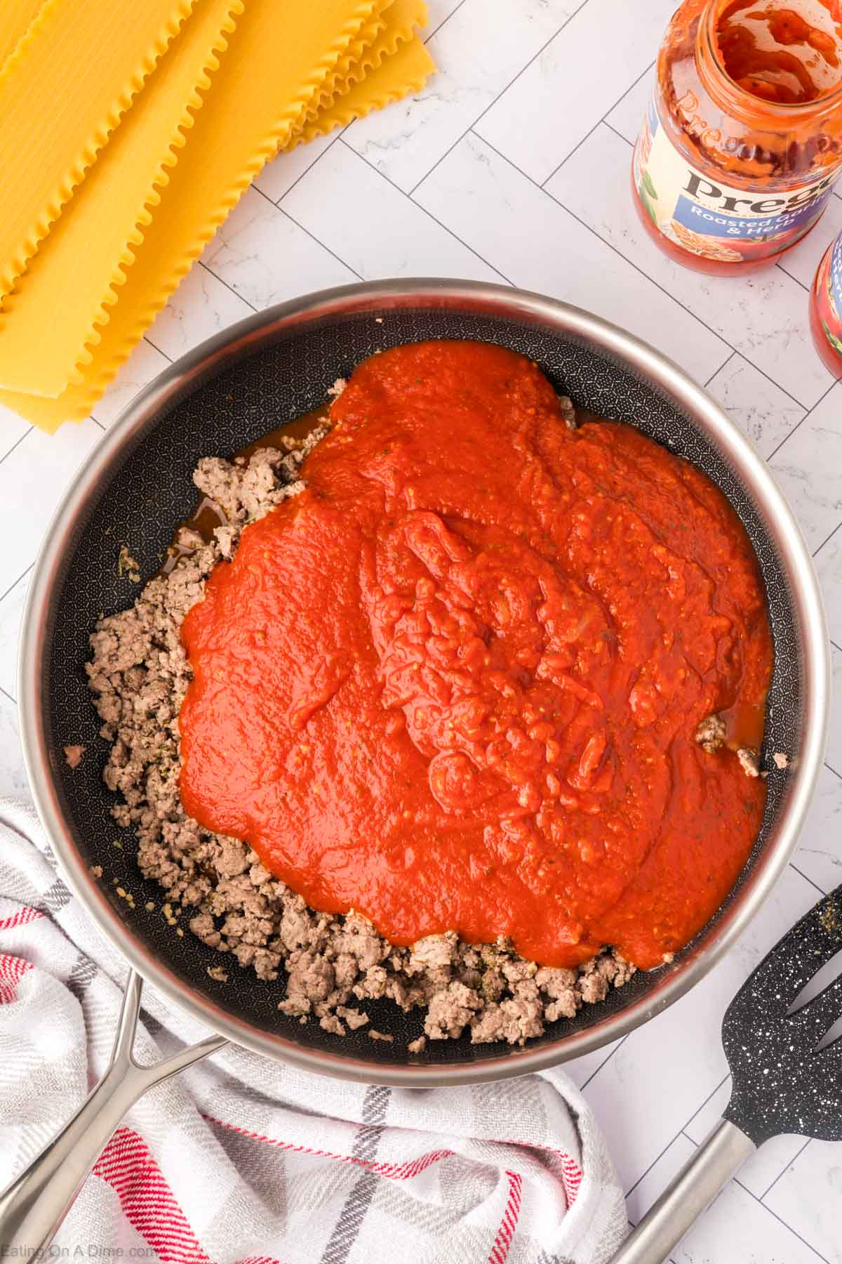 Pouring the sauce in the skillet with the cooked ground beef