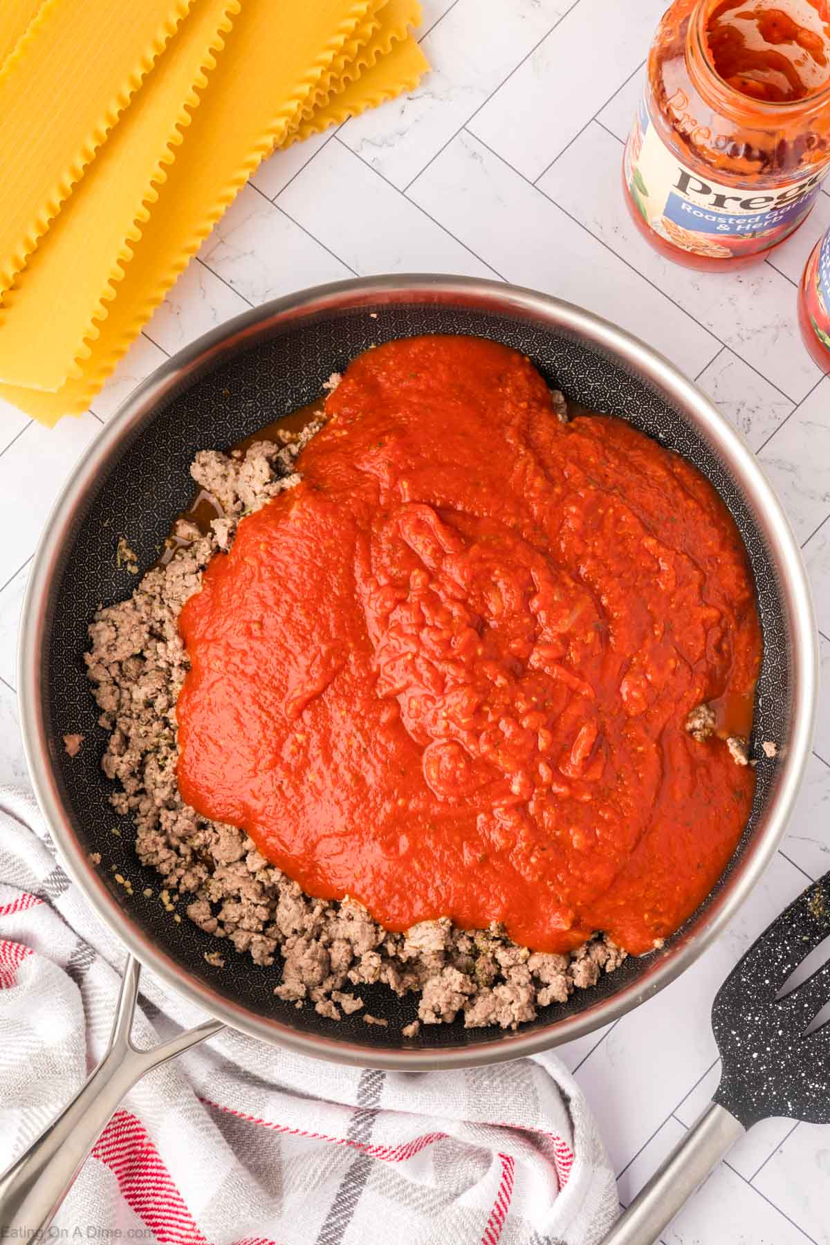 Pouring the sauce in the skillet with the cooked ground beef