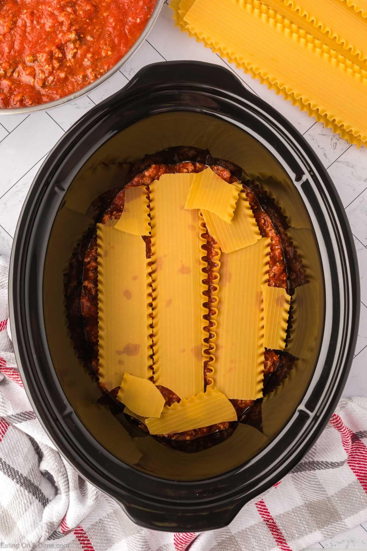 Placing the noodles on the sauce in the slow cooker