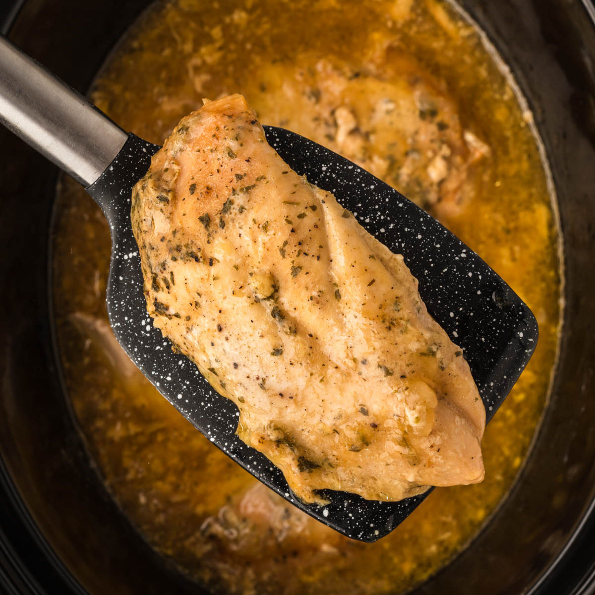Ranch chicken in the slow cooker with a serving on a spatula