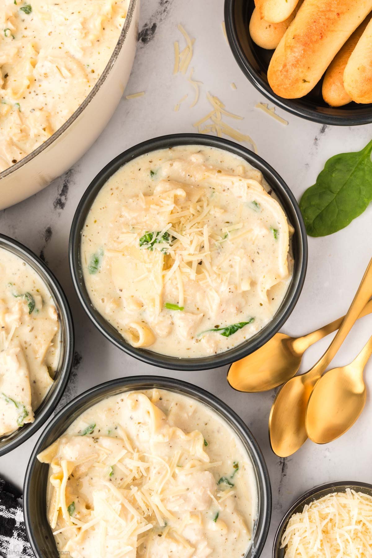 White Lasagna Soup in a black bowl topped with fresh parmesan cheese