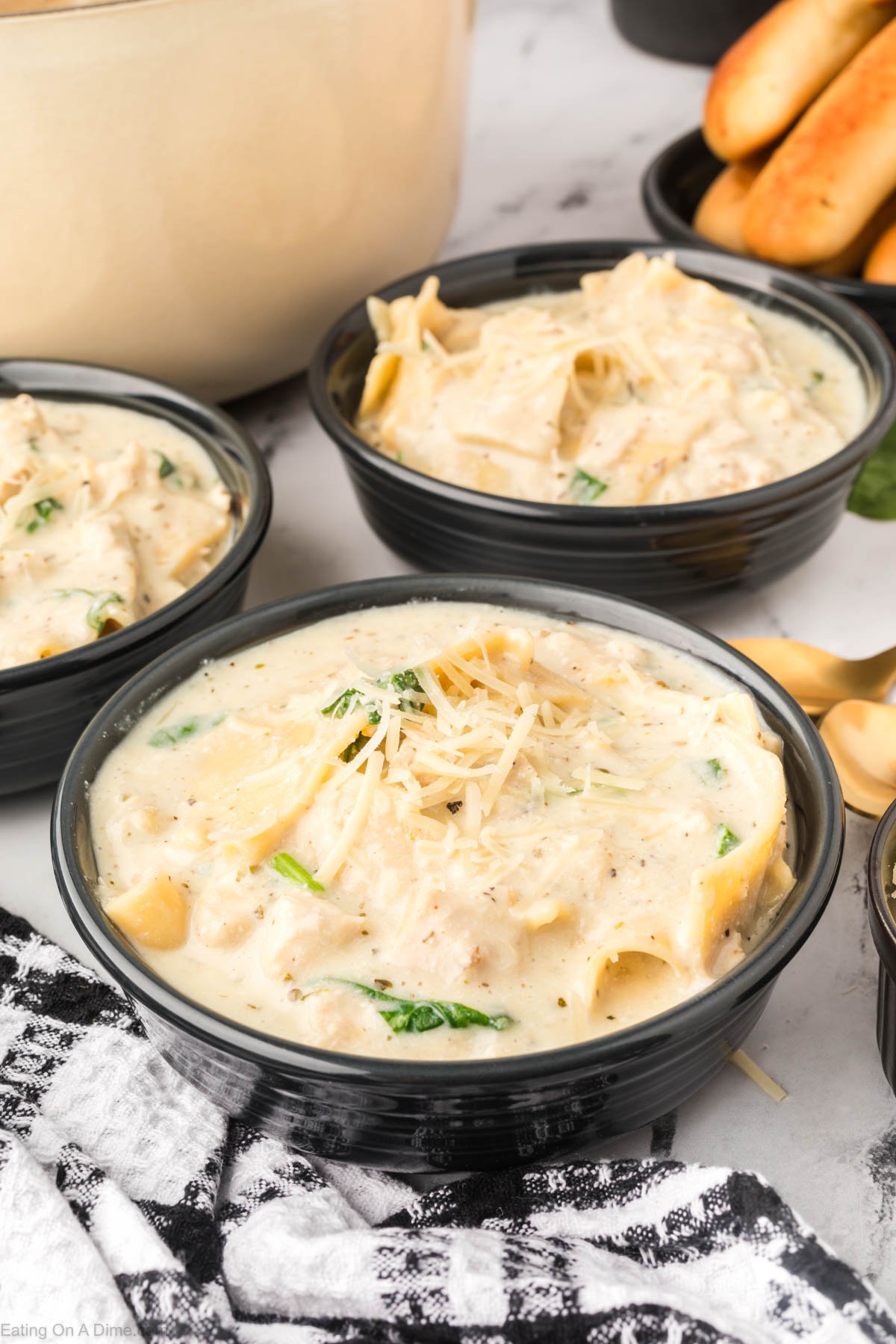 White Lasagna Soup in a black bowl topped with fresh parmesan cheese