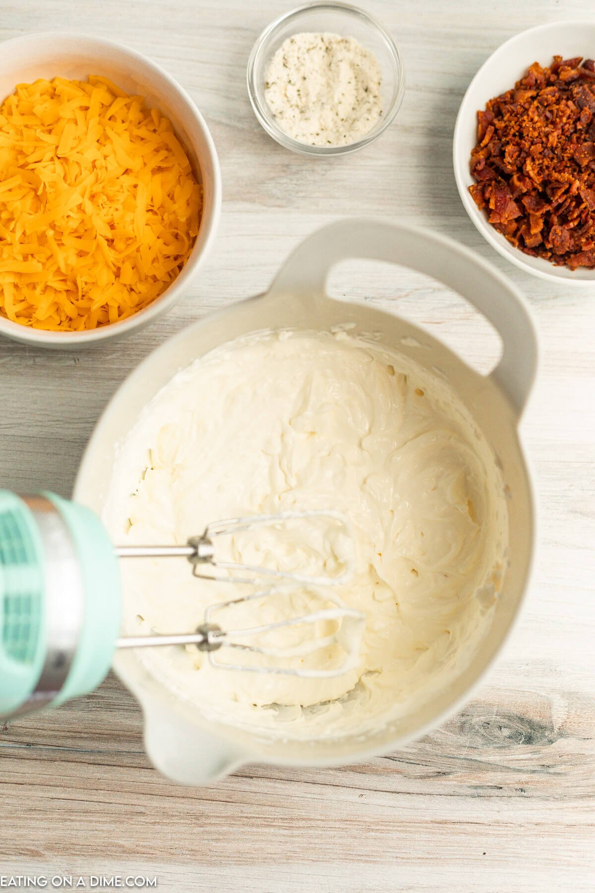 Bowl with sour cream and cream cheese combined with a mixer. 