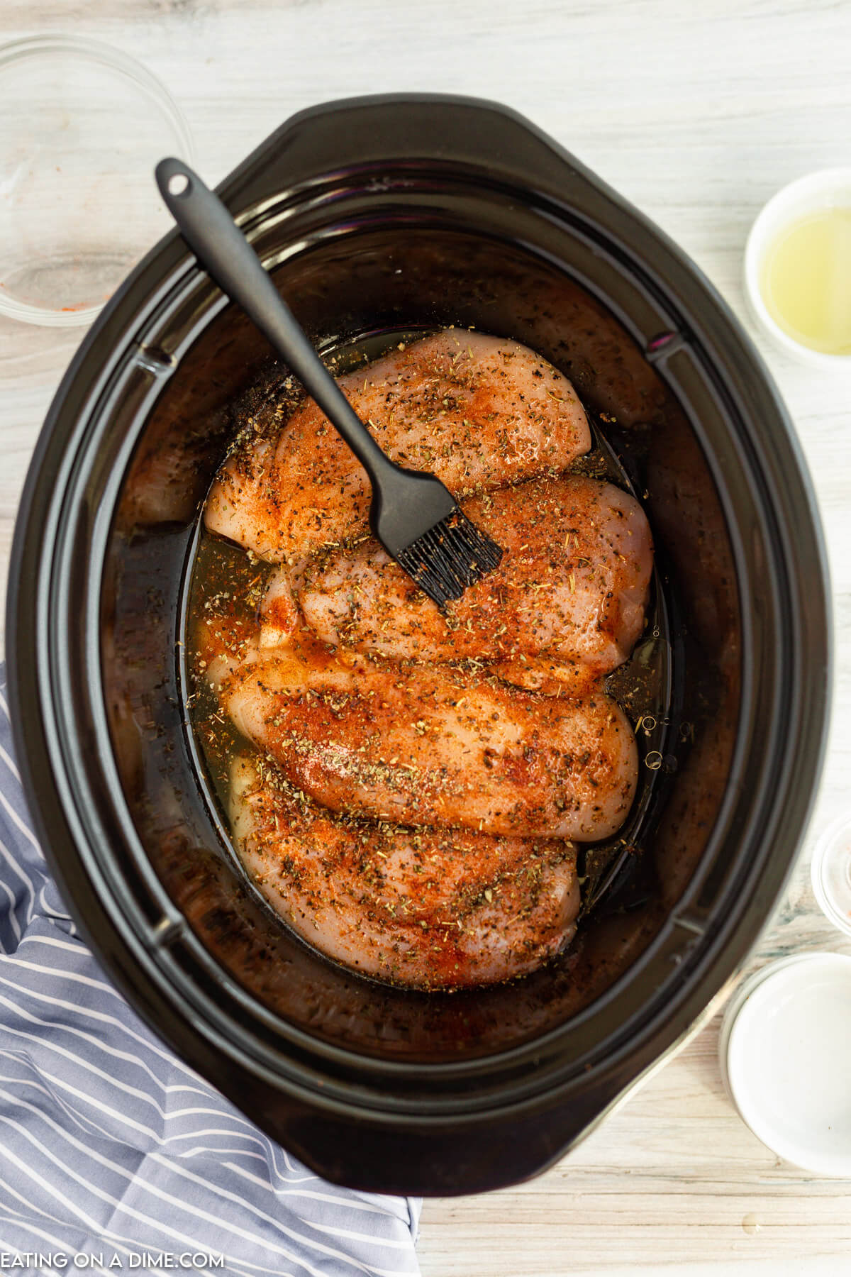 Basting chicken with seasoning and oil in the slow cooker