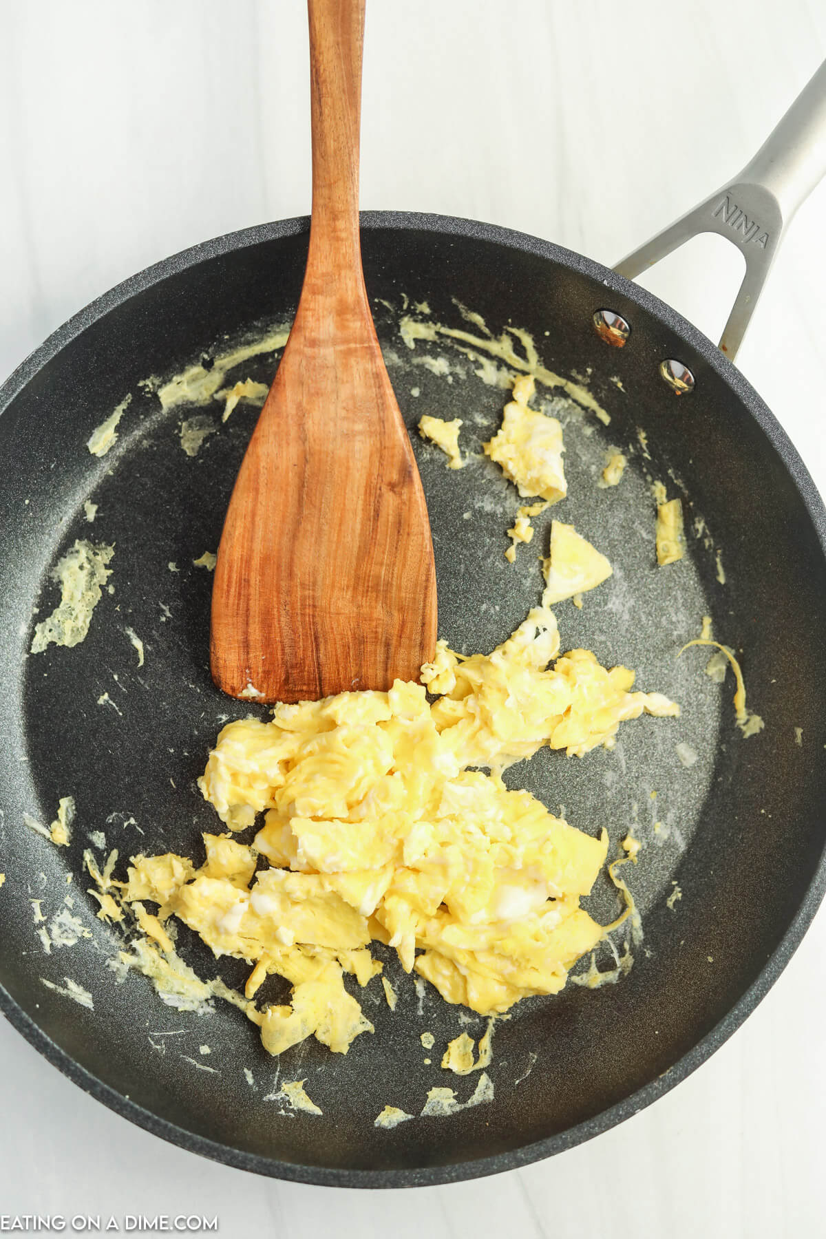 Cooking the eggs in a skillet with a wooden spoon