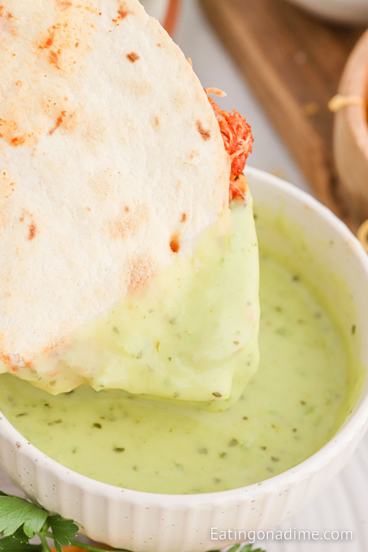 Dipping chicken quesadilla in a green sauce