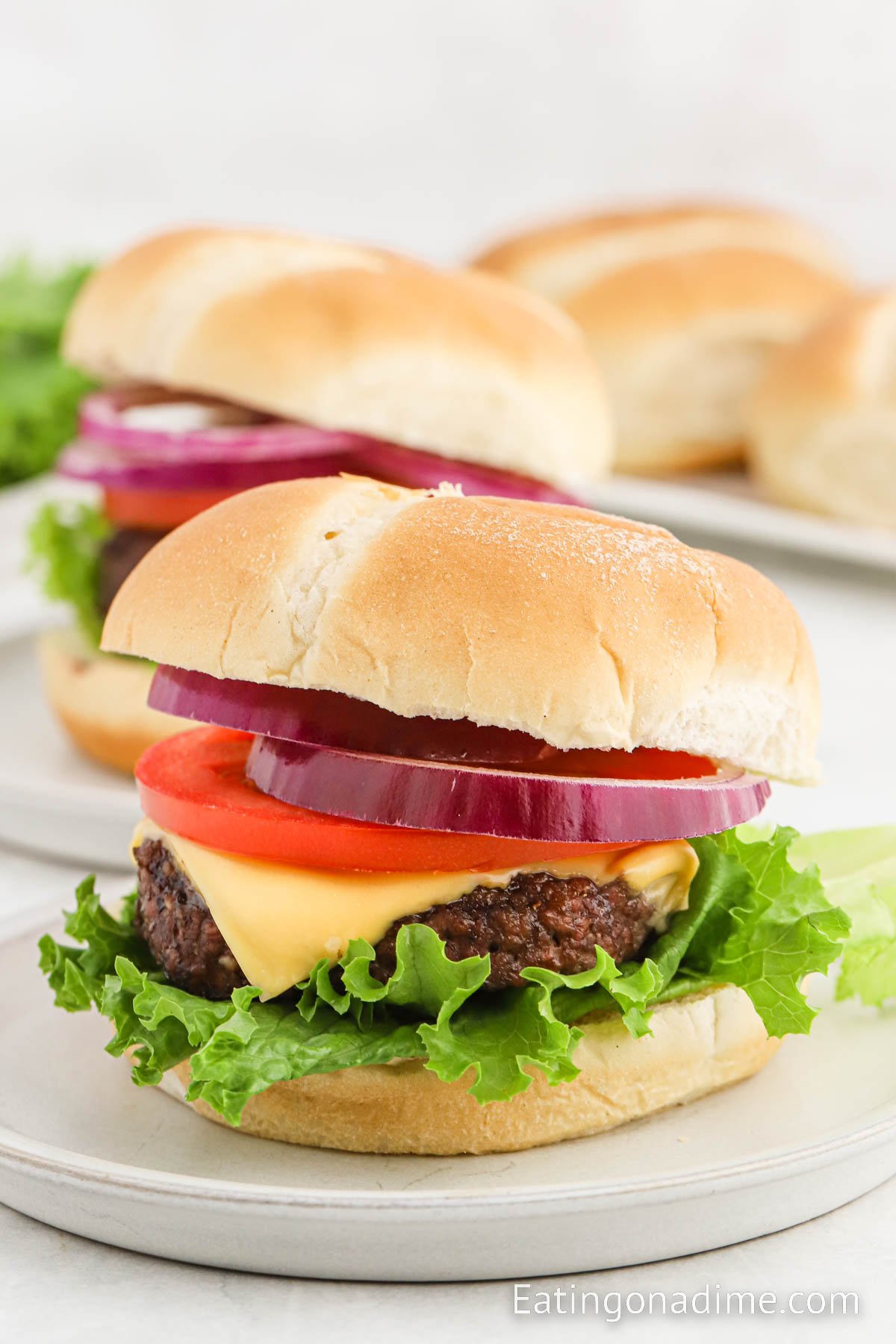 Baked burger pattie topped with cheese, tomato, onions and lettuce on a plate