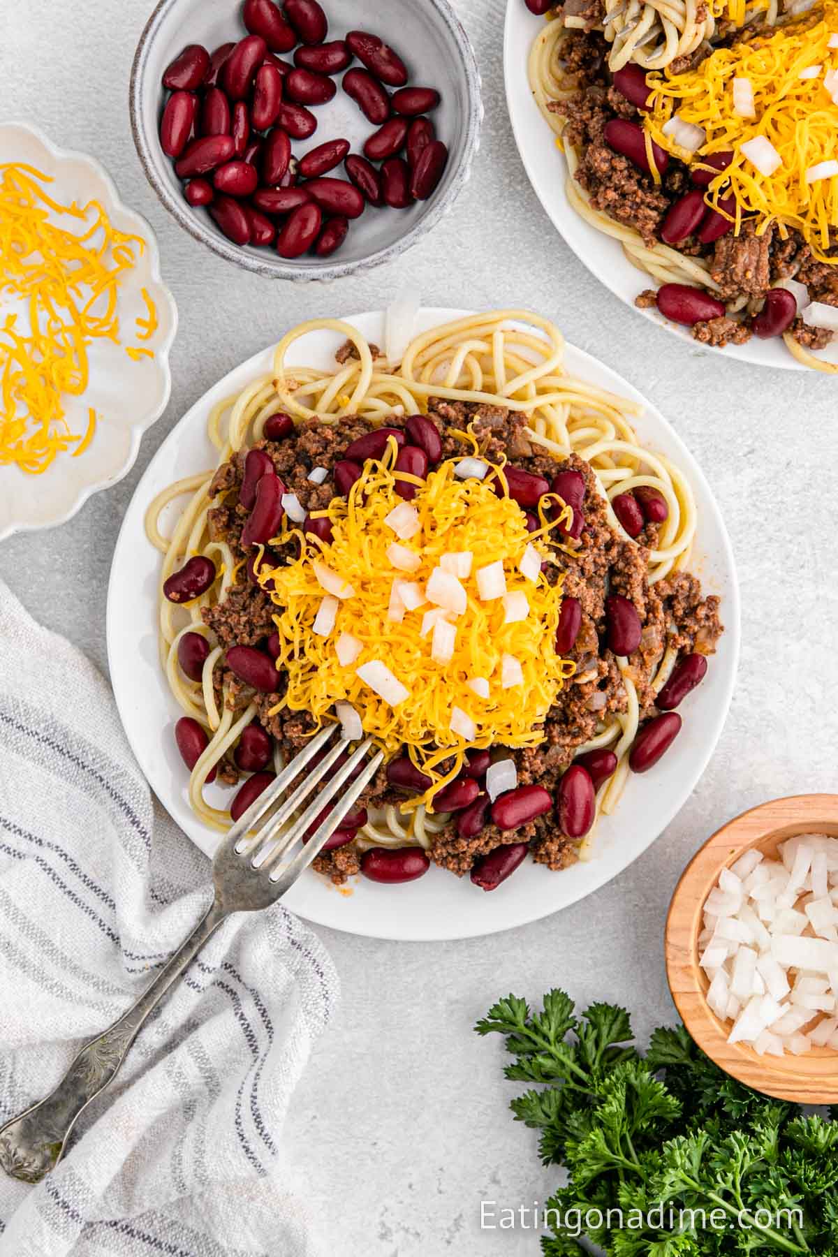Cincinnati Chili on a plate with spaghetti topped with cheese and onions