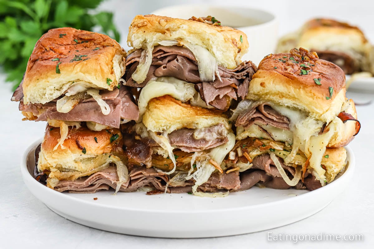 French Dip Sliders stacked on a white plate.