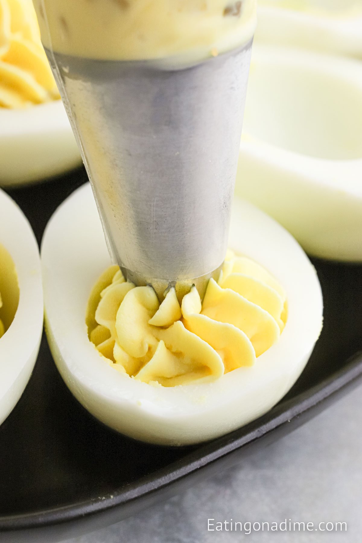 Filling the egg whites with the yolk mixture in a piping bag