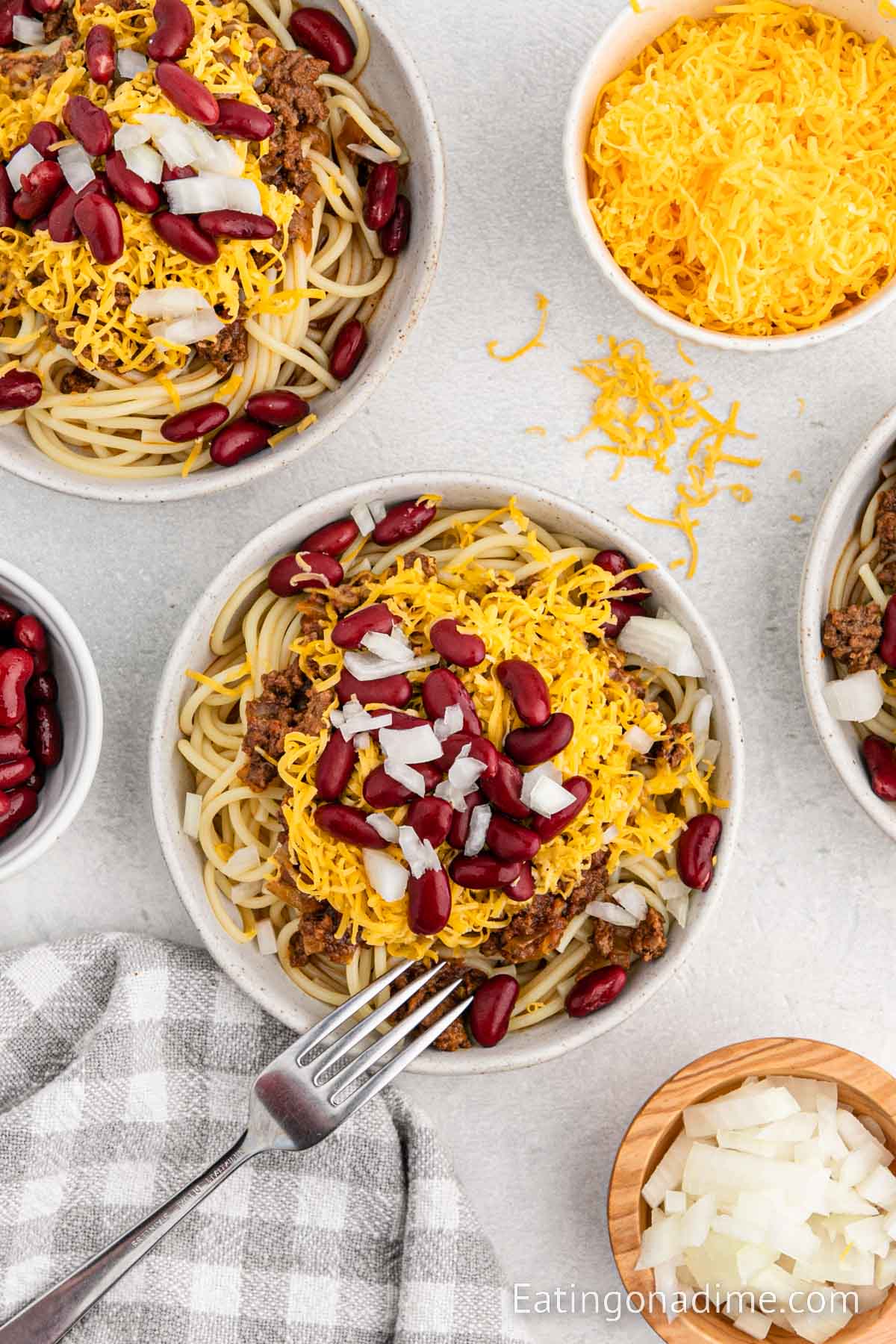 Close up image of Cincinnati Chili on cooked noodles in a bowl with a fork
