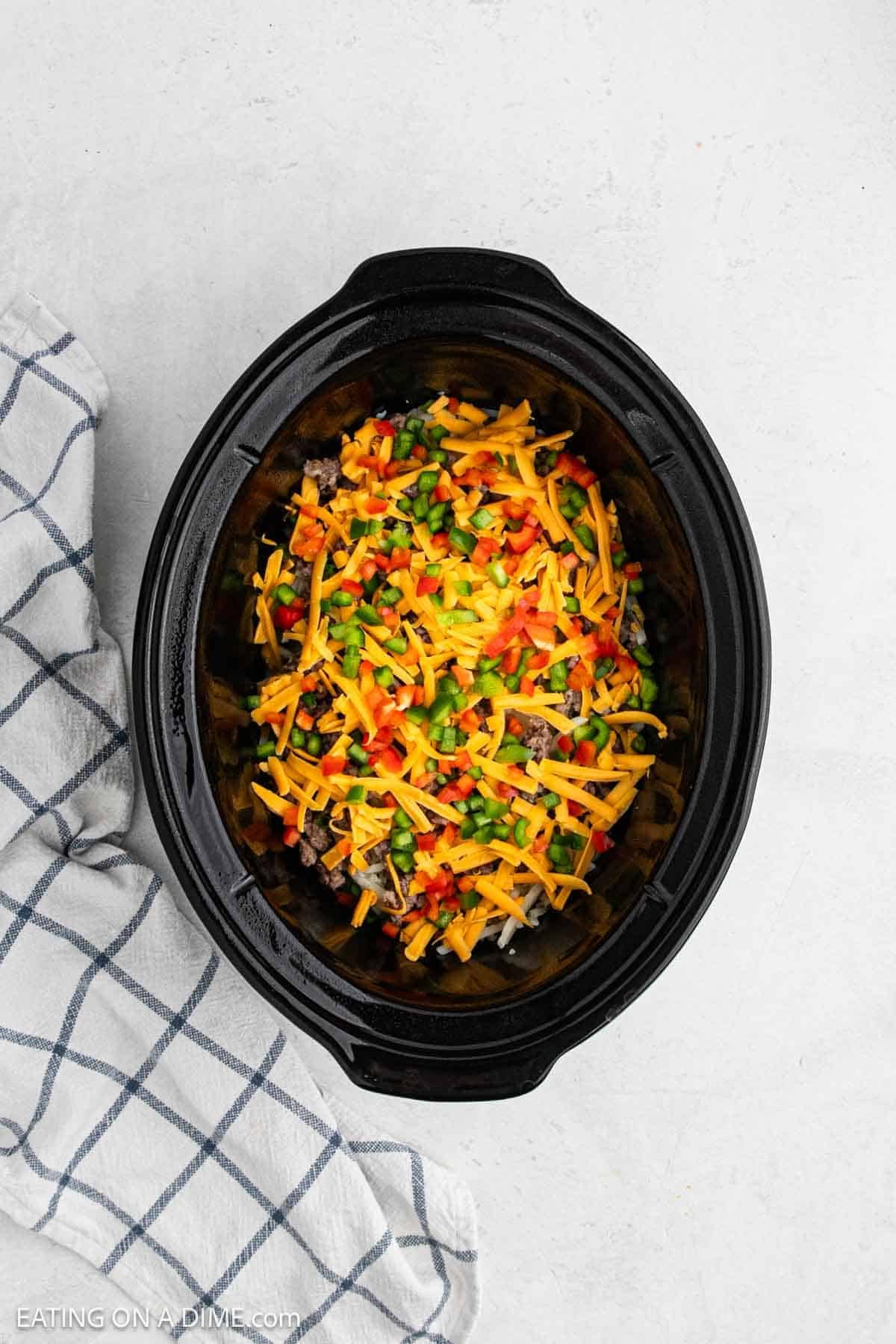 Shredded cheese and chopped veggies in the crockpot.