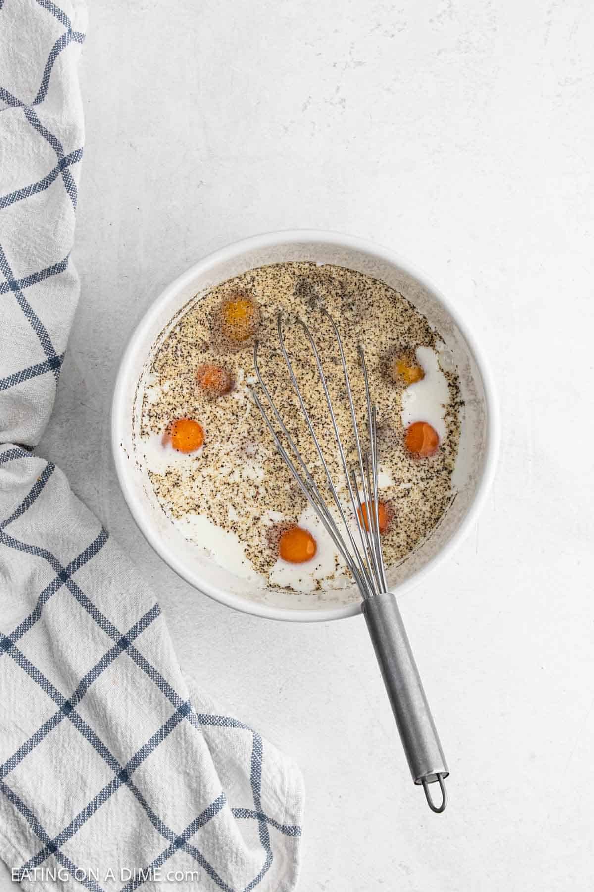 Whisking eggs, spices and milk in a bowl.