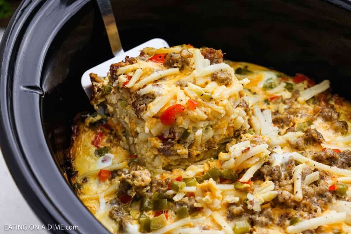 A serving of breakfast casserole on a spatula and the rest in the crockpot.