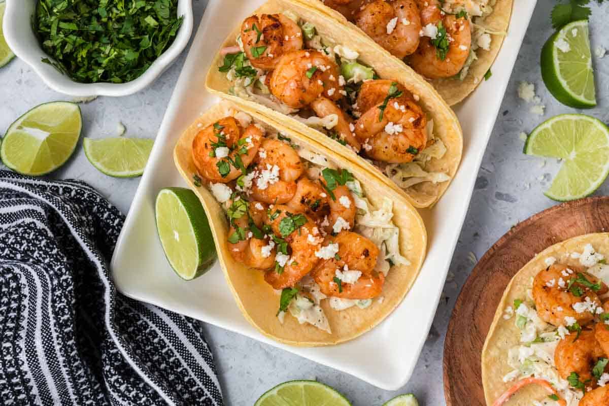 Blackened Shrimp tacos on a platter topped with fresh chopped cilantro and cojita cheese.