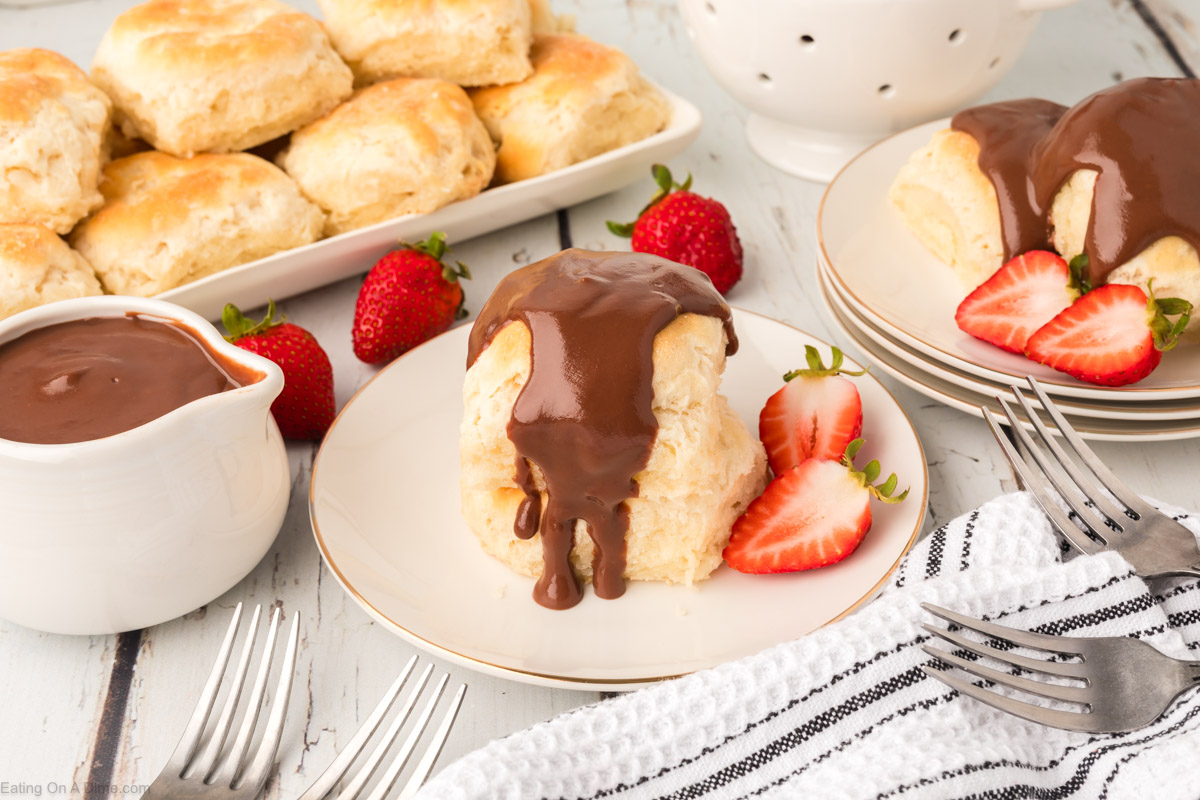 Chocolate gravy poured over a biscuit on a plate with fresh strawberries on the side.